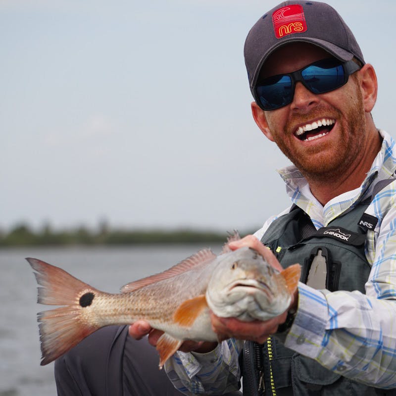 Robert holding up a redfish and smiling at the camera.