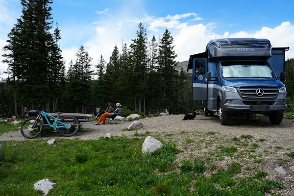 The Bauers sit beside their Tiffin Wayfarer Class C Motorhome in Medicine Bow-Routt National Forest