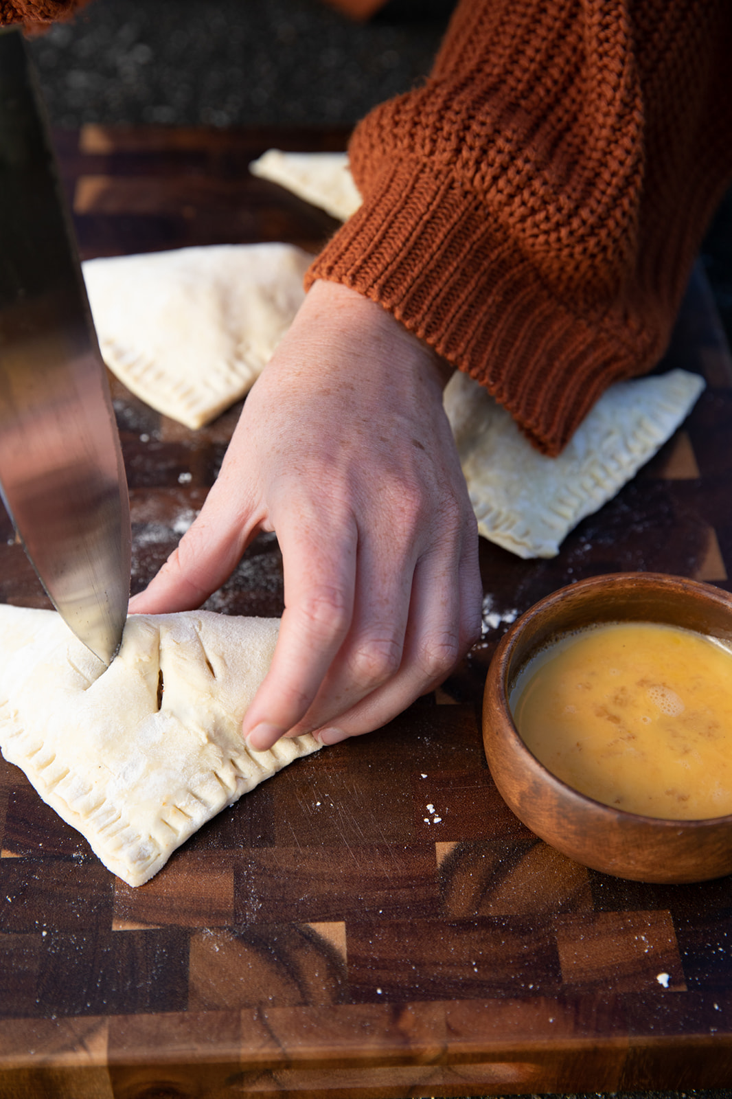 Cutting slits into folded hand pies before brushing with egg wash.