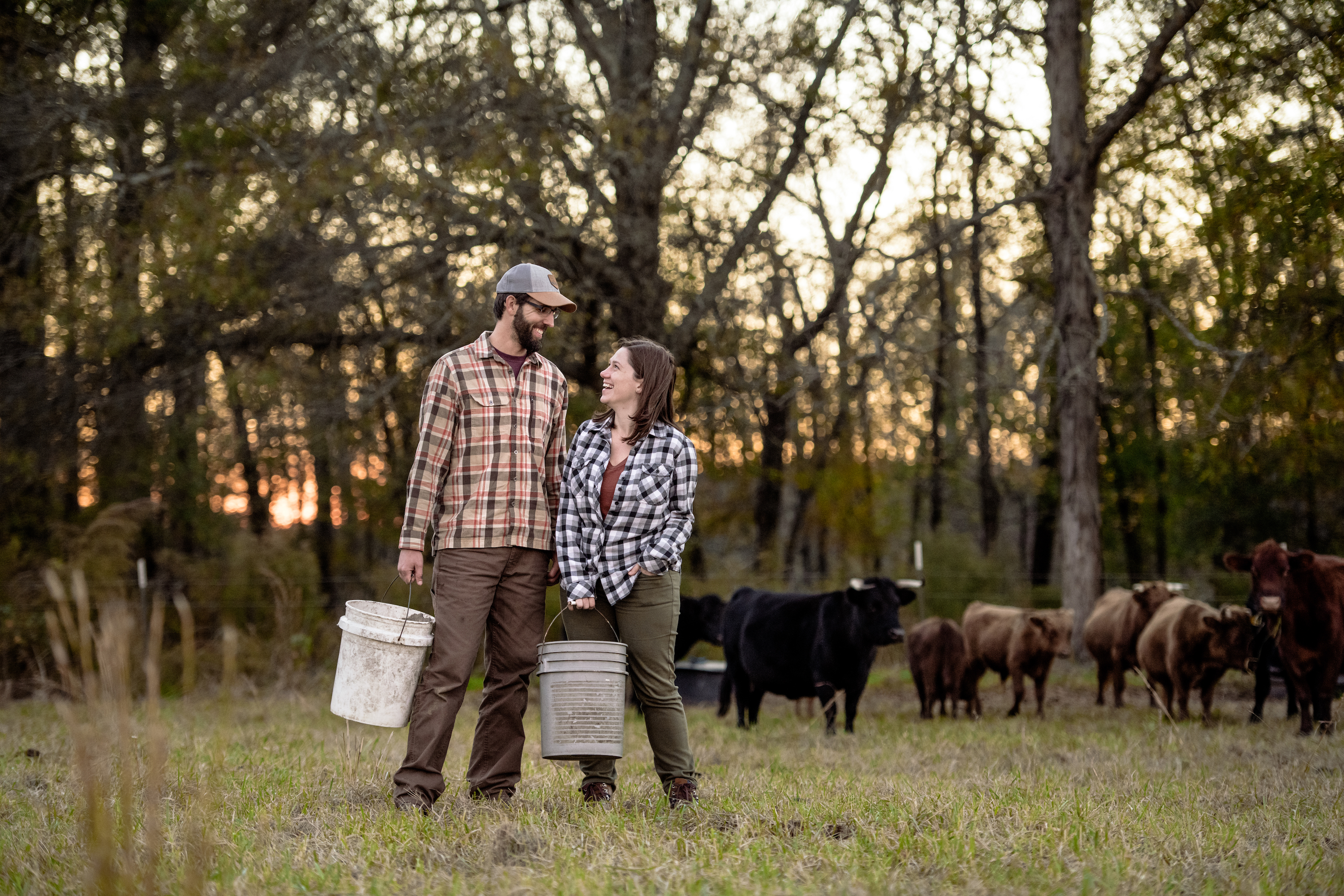 Todd & Marcia Schabel smile at each other holding buckets of crops on a farm.