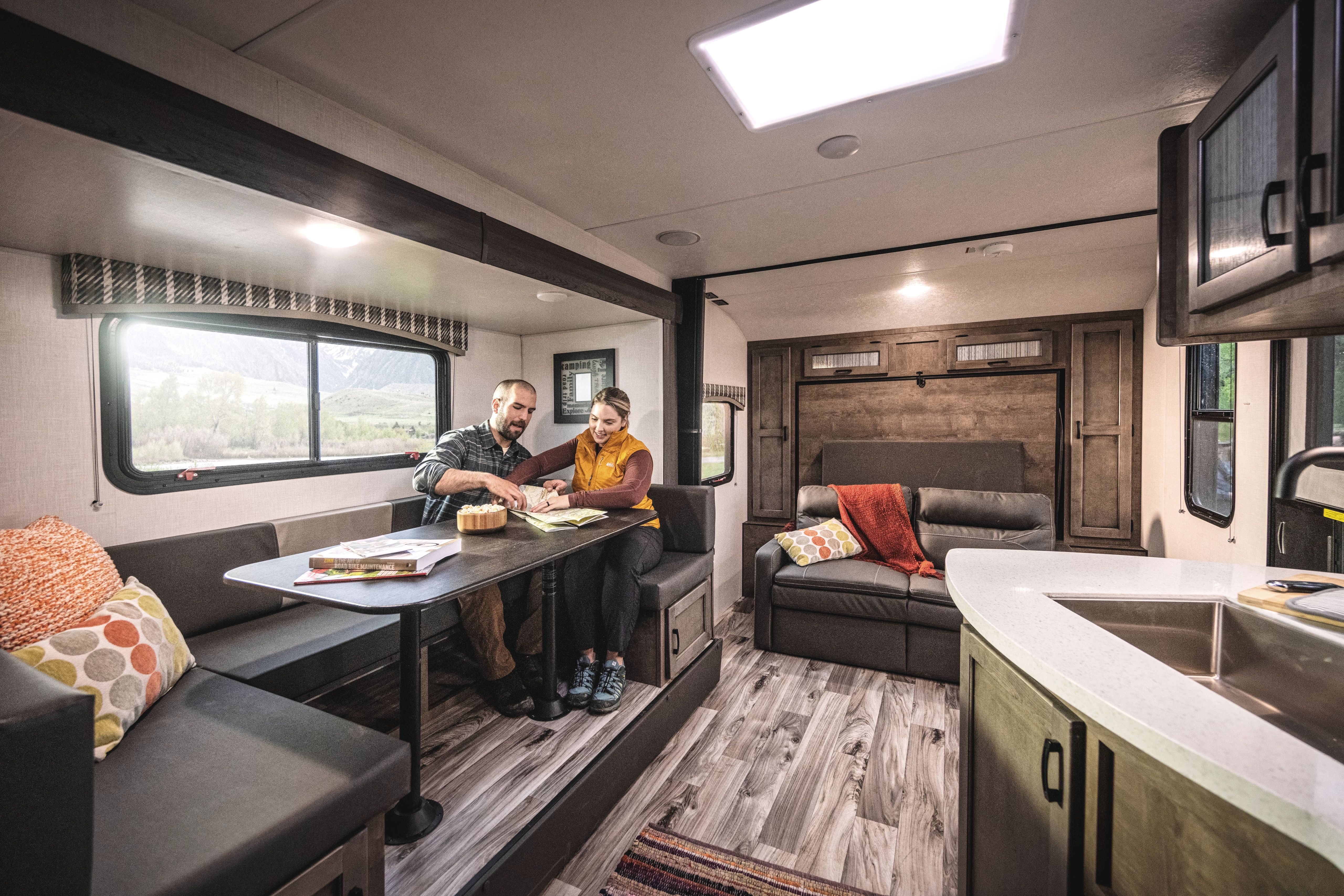 A couple looks at a map at a dinette inside of a venture sonic x rv