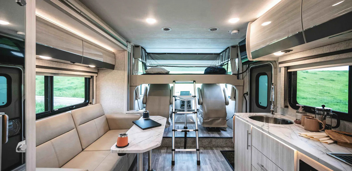 The interior of a Class A Motorhome, featuring the living area, kitchen, bunk, and driving dashboard.