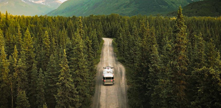 Stacey Power's Airstream driving through a forest towards a mountain