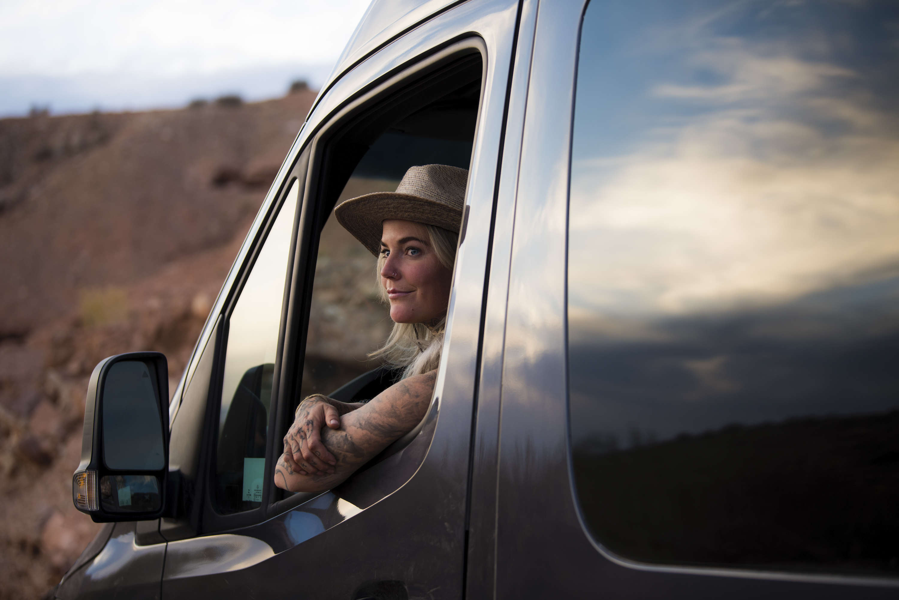 A woman sits in a Class B van looking out the window.
