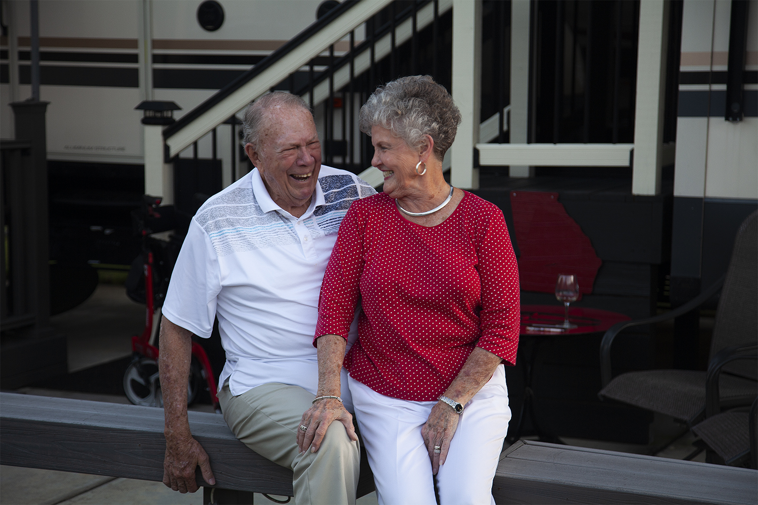 A senior man and woman laughing together as they are posed for a portrait. 