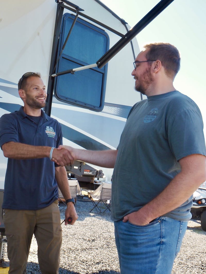 A THOR's mobile RV repair technician shaking Bailey Damberg's hand in front of their RV
