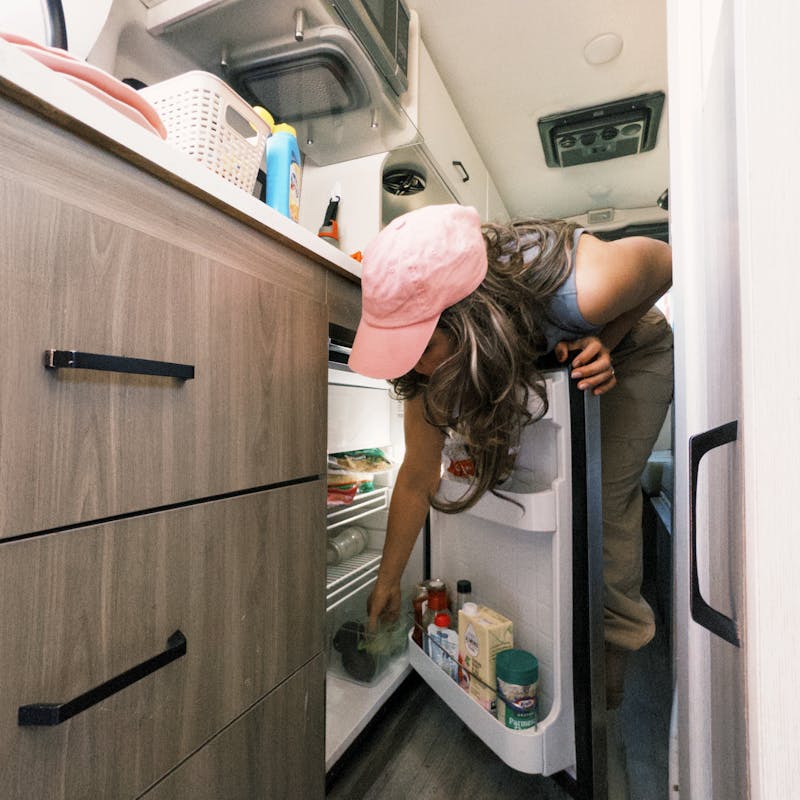 Sara Arango opening the fridge in their camper van