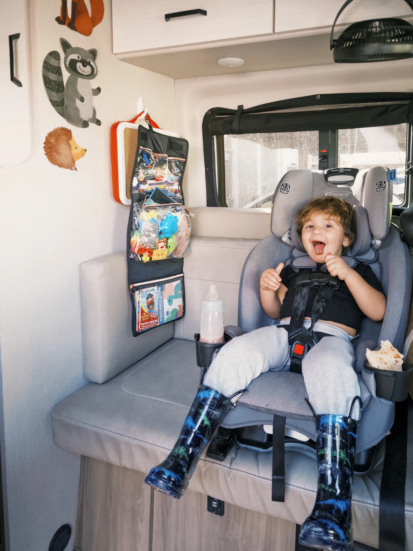 A toddler strapped into a carseat inside of a camper van 