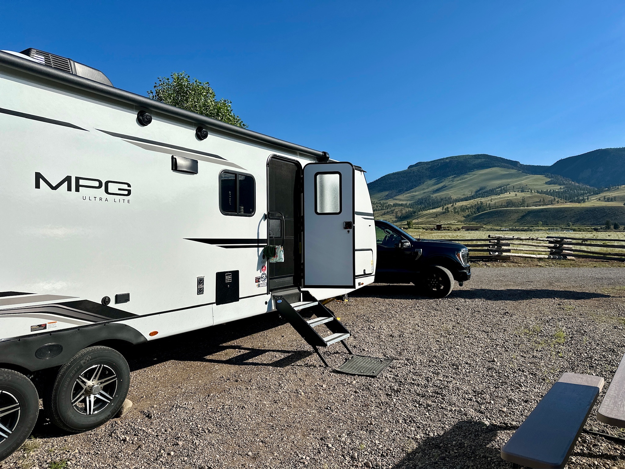 a travel trailer boondocking in a gravel lot with rolling hills in the background 