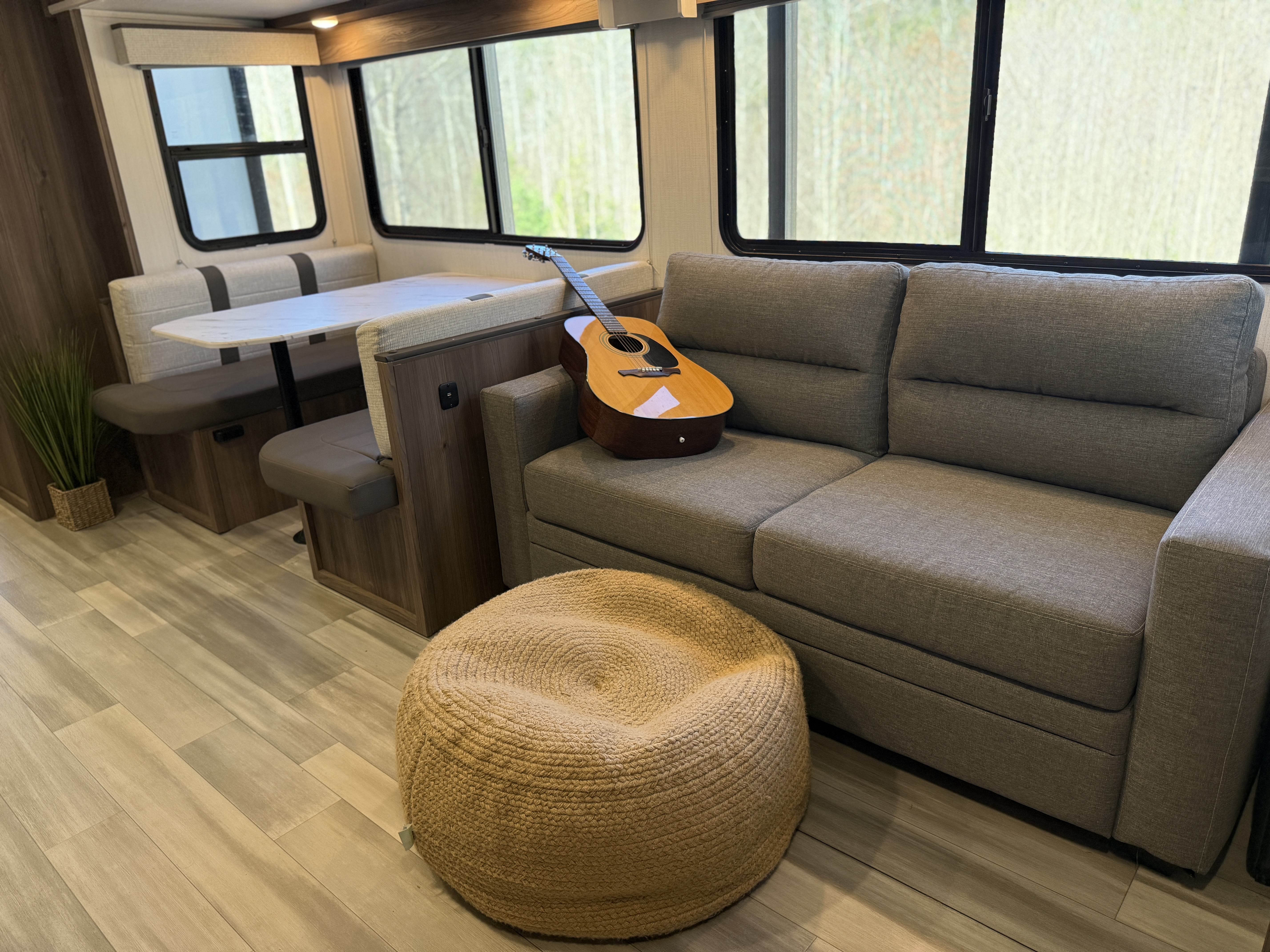 a guitar resting on the couch next to a dinette inside a cruiser mpg travel trailer rv 