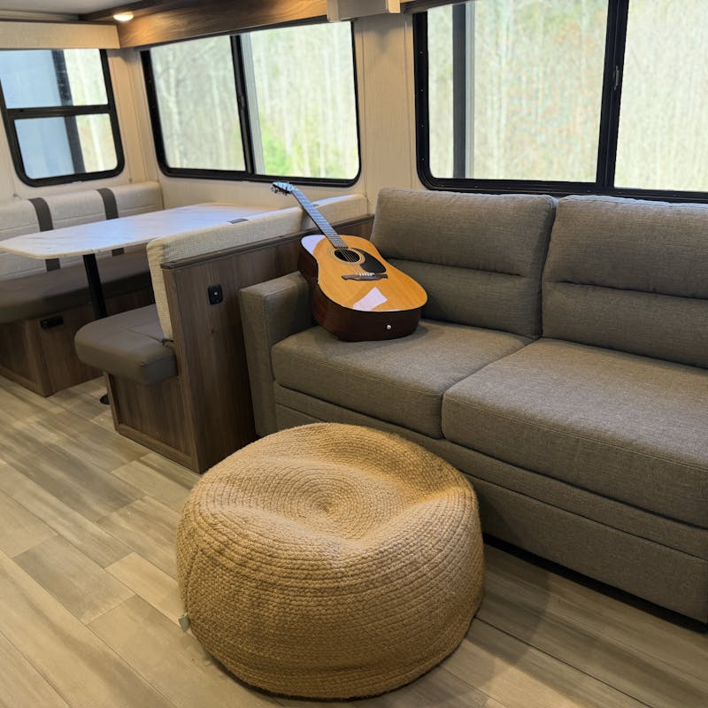 a guitar resting on the couch next to a dinette inside a cruiser mpg travel trailer rv