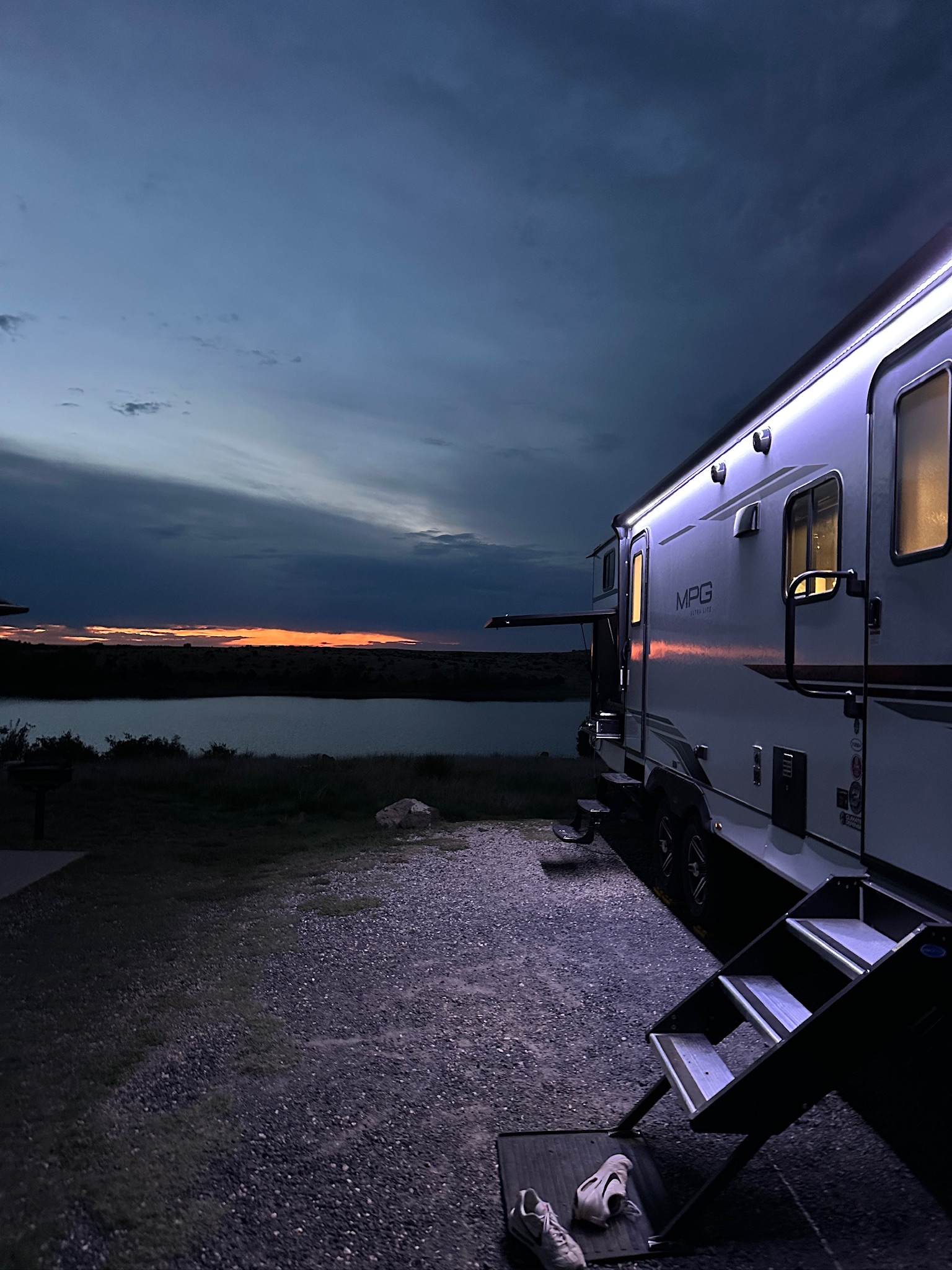a travel trailer parked next to a lake at dusk 