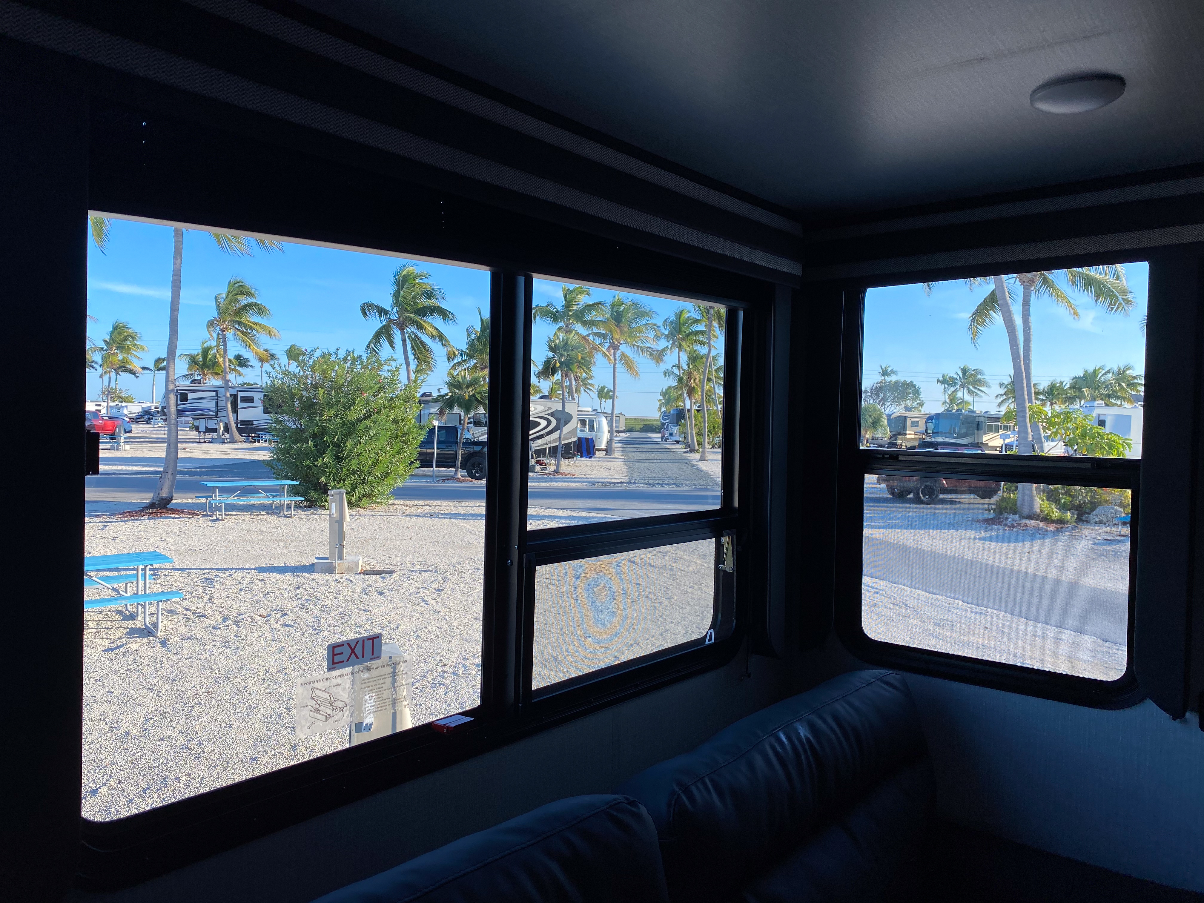 A view outside of an RV window of a sandy, beachy RV campground