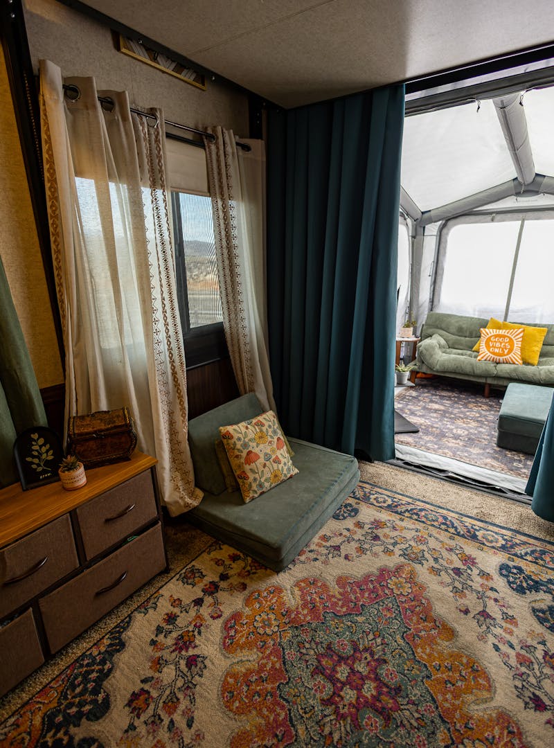 the garage area of a toy hauler with a cozy rug, curtains and chair
