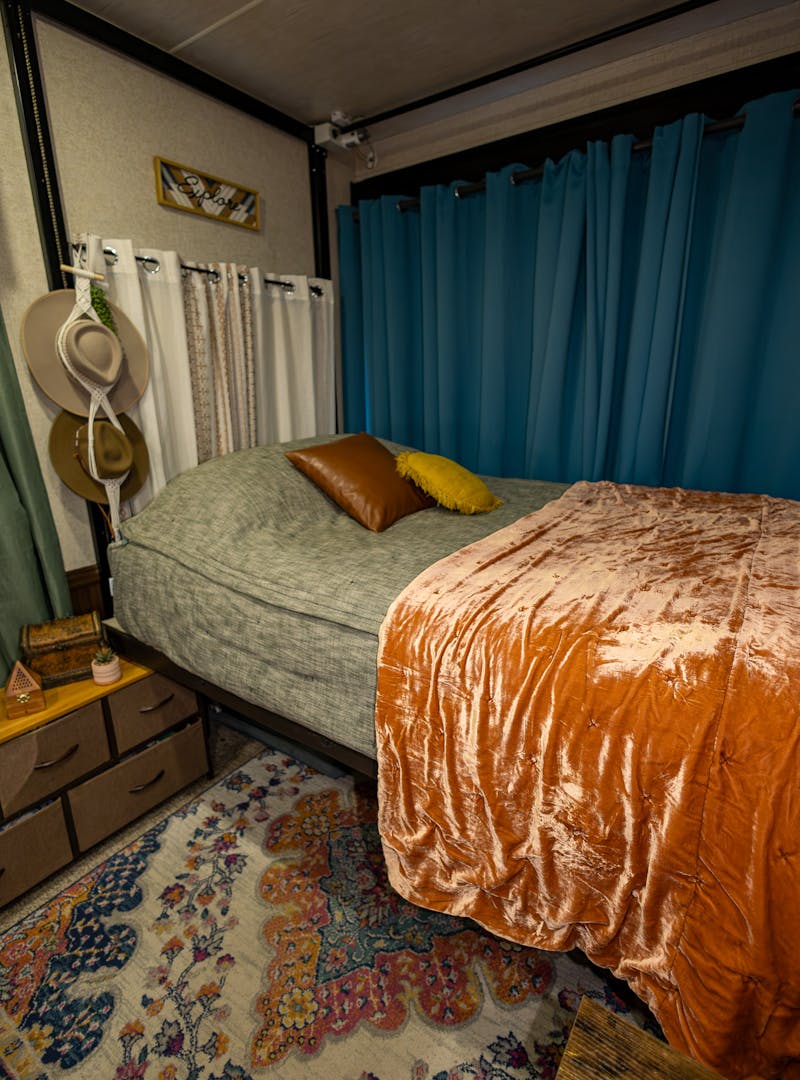 A bunked in the garage of a toy hauler RV with cozy blankets and pillows