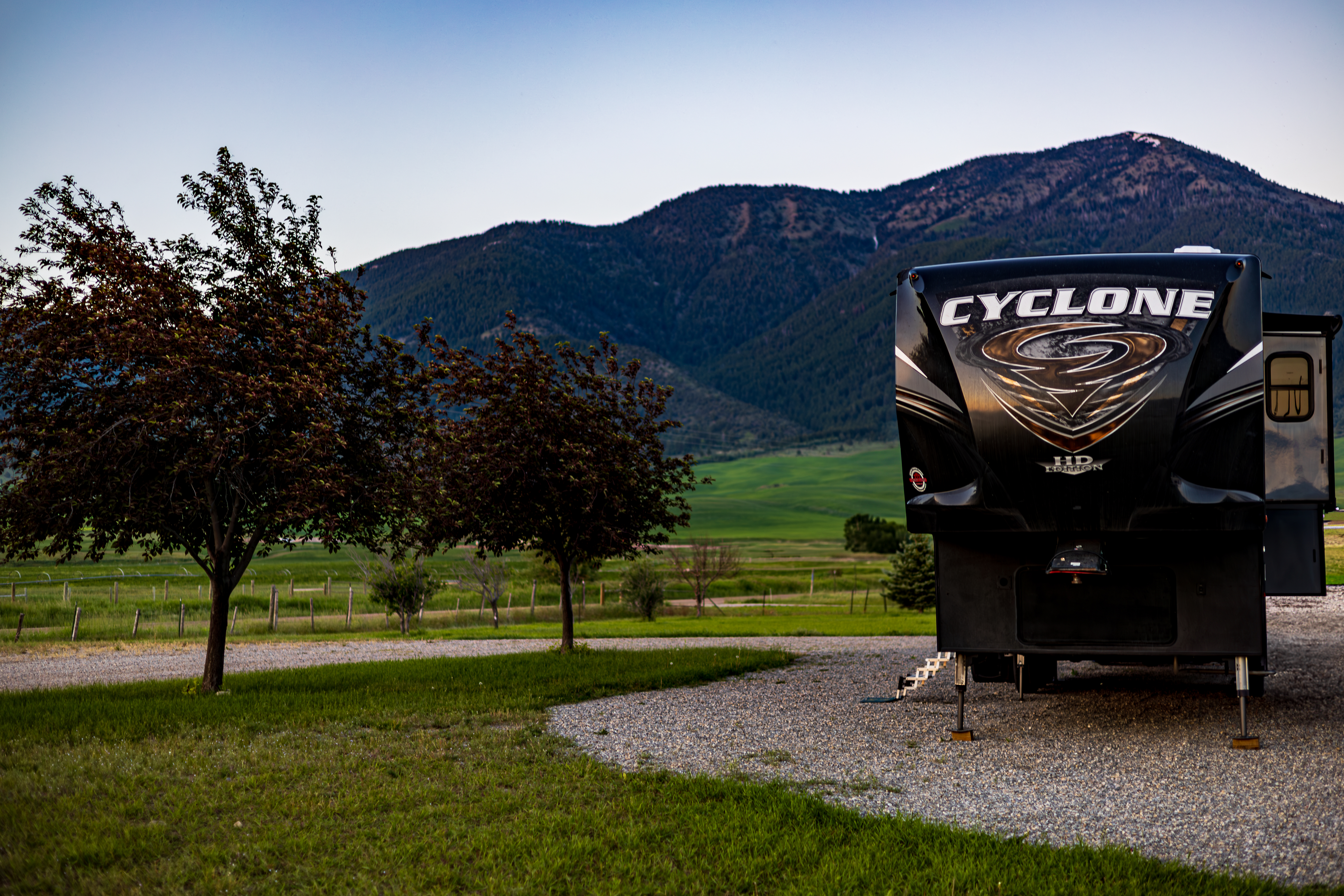 A heartland cyclone fifth wheel on a gravel campsite with mountain views