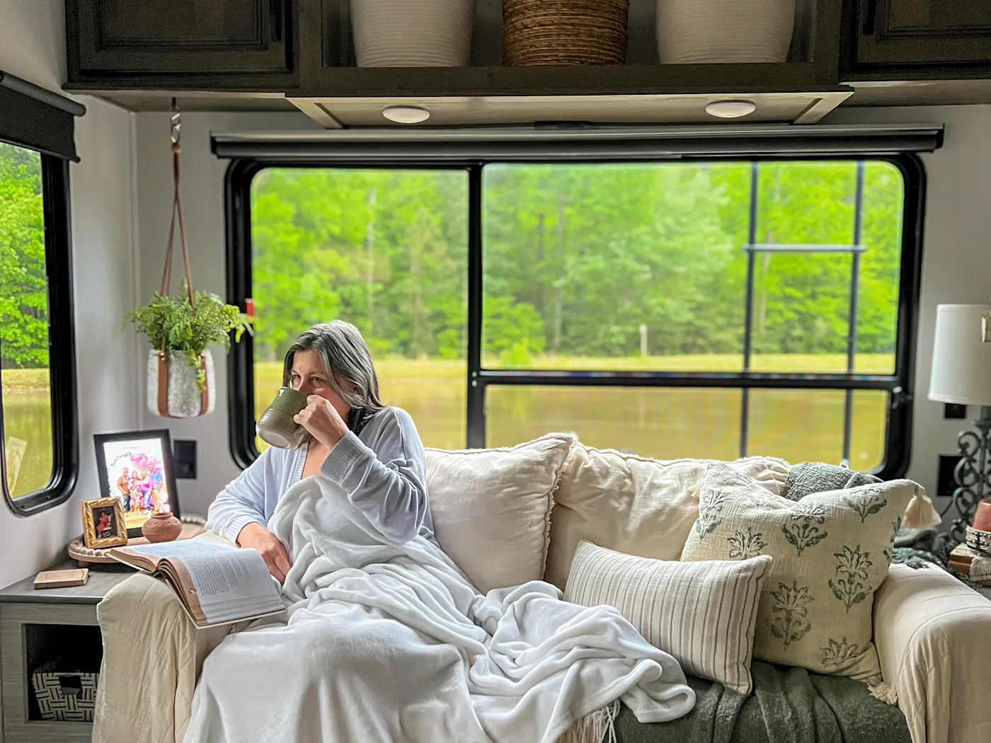 Tammy benedict siggin on her cozy sofa sipping on coffee and reading a book