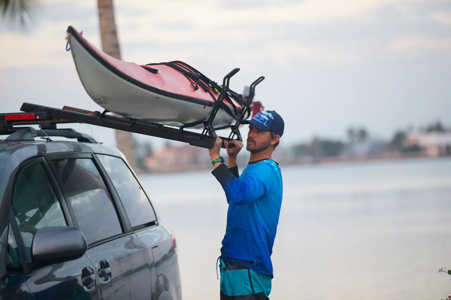 A man mounting a kayak on top of a vehicle 