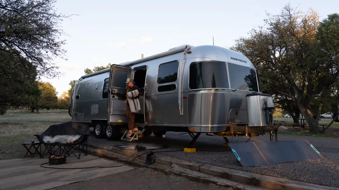 Karen Blue stepping out the door of her Airstream Flying Cloud travel trailer.
