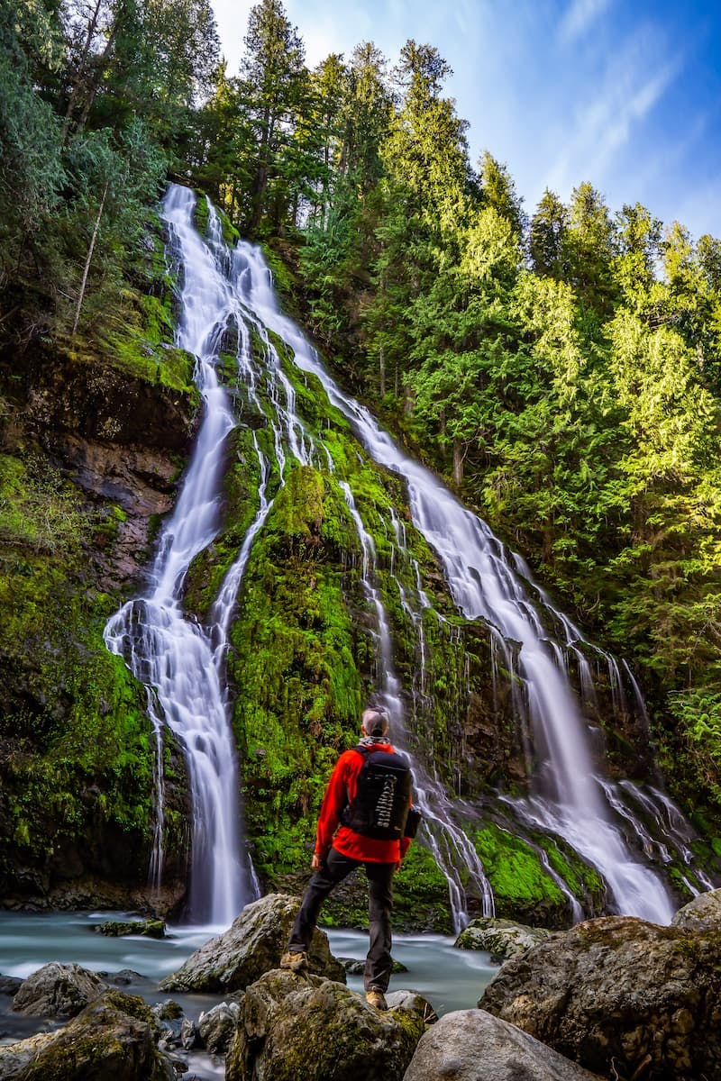 A man looking at a waterfall in Mt. Baker National Forest