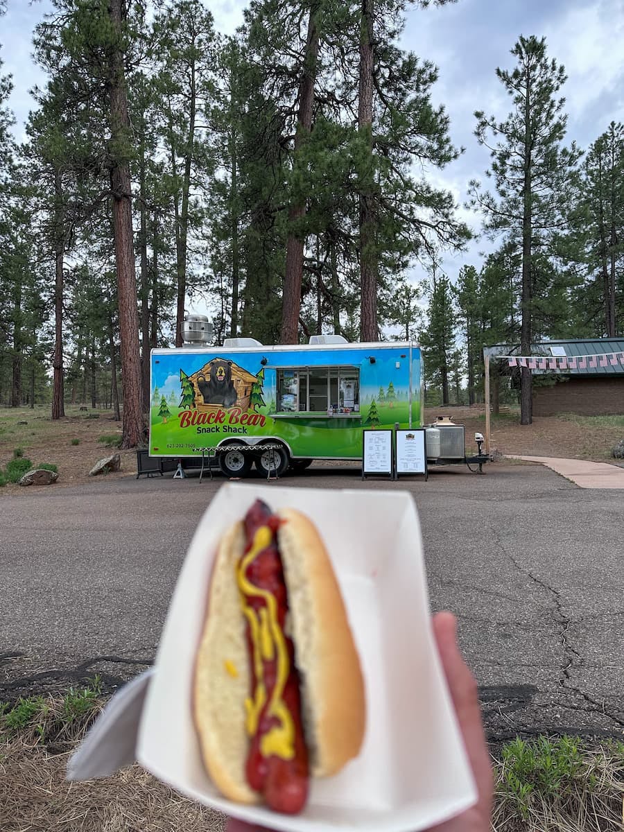 Jeff Poe holding up a hot dog in Kaibab National Forest