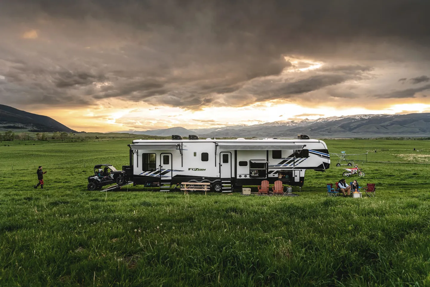 A group of friends with a fifth wheel RV boondocking in a field.