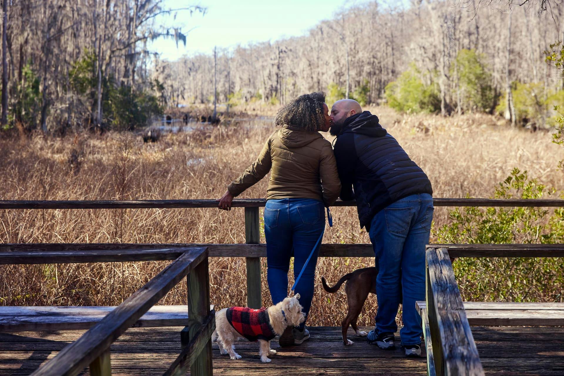Gabe and Rocio Rivero kissing with their dogs at their feet.