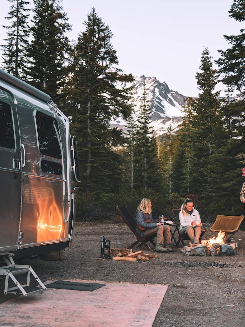 Karen Blue and her family sitting around a fire while boondocking in a forest.