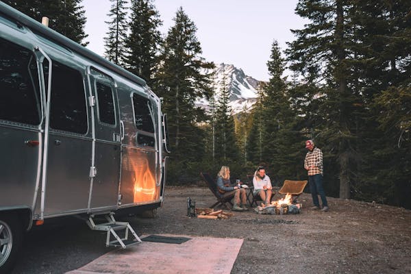 Karen Blue and her family sitting around a fire while boondocking in a forest.
