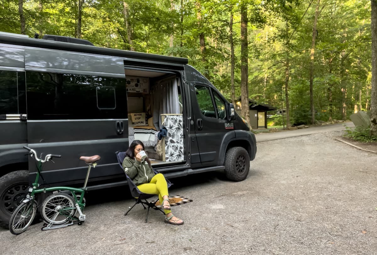 Jess Lawson sitting outside of her camper van at her campsite in Cherokee National Forest.