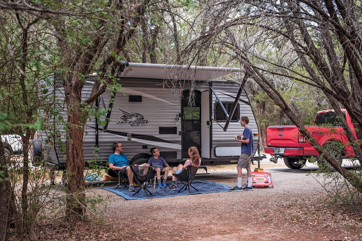 Alison Takacs and her family sitting in front of their RV at their campsite in Dinosaur Valley State Park.