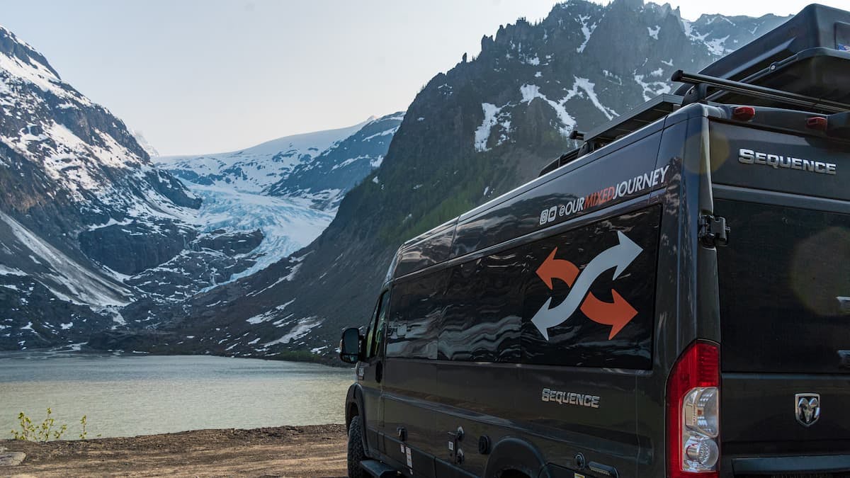 Gabe and Rocio Rivero's campervan parked in front of a lake with snowy mountains.