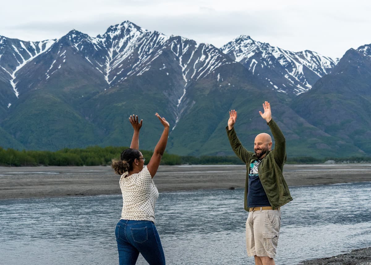 Gabe and Rocio Rivero smiling with their arms raised in front of mountains.
