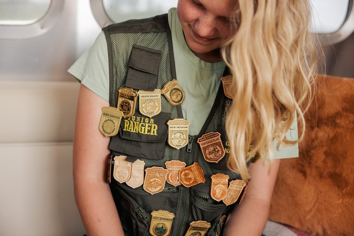 Karen Blue's daughter wearing her Junior Ranger vest with badges from different national parks.