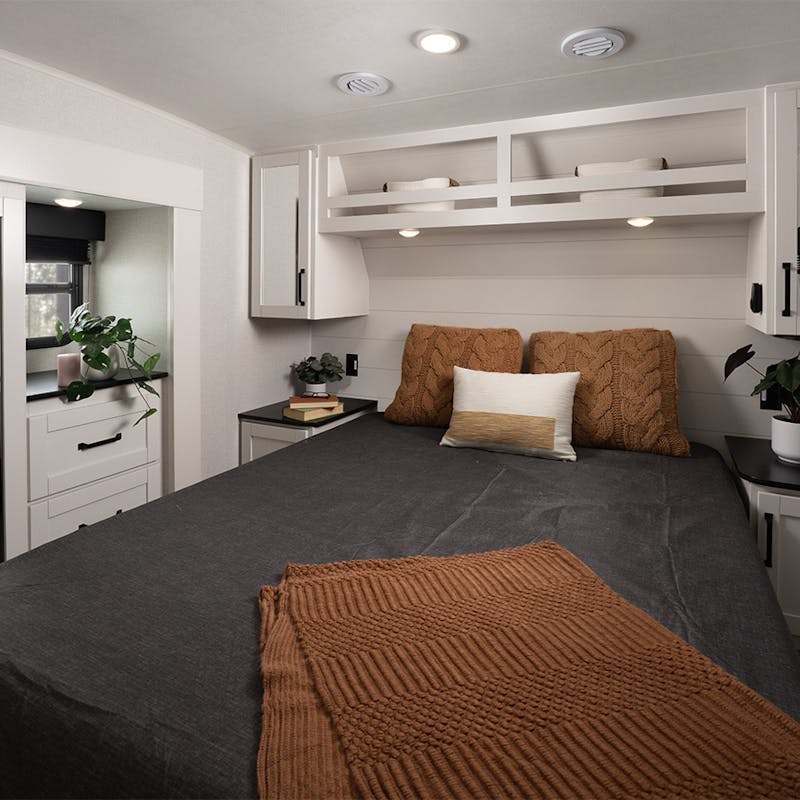 A large, cozy bedroom inside of an Open Range roamer fifth wheel/