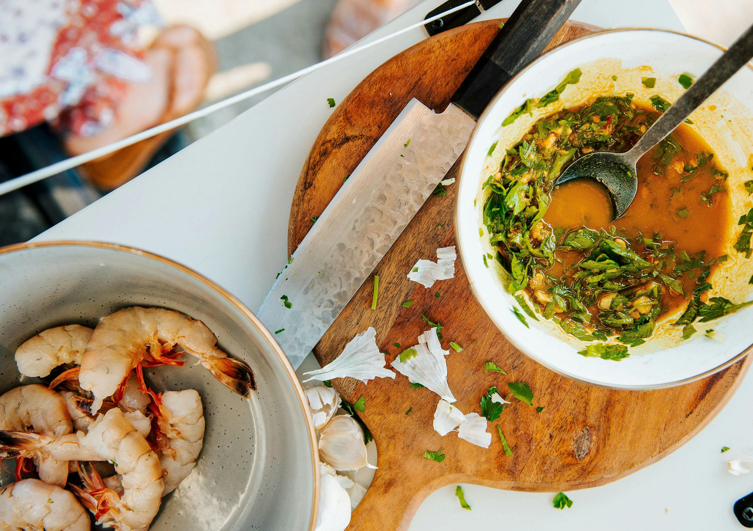 Shrimp in a bowl next to a bowl of marinade 