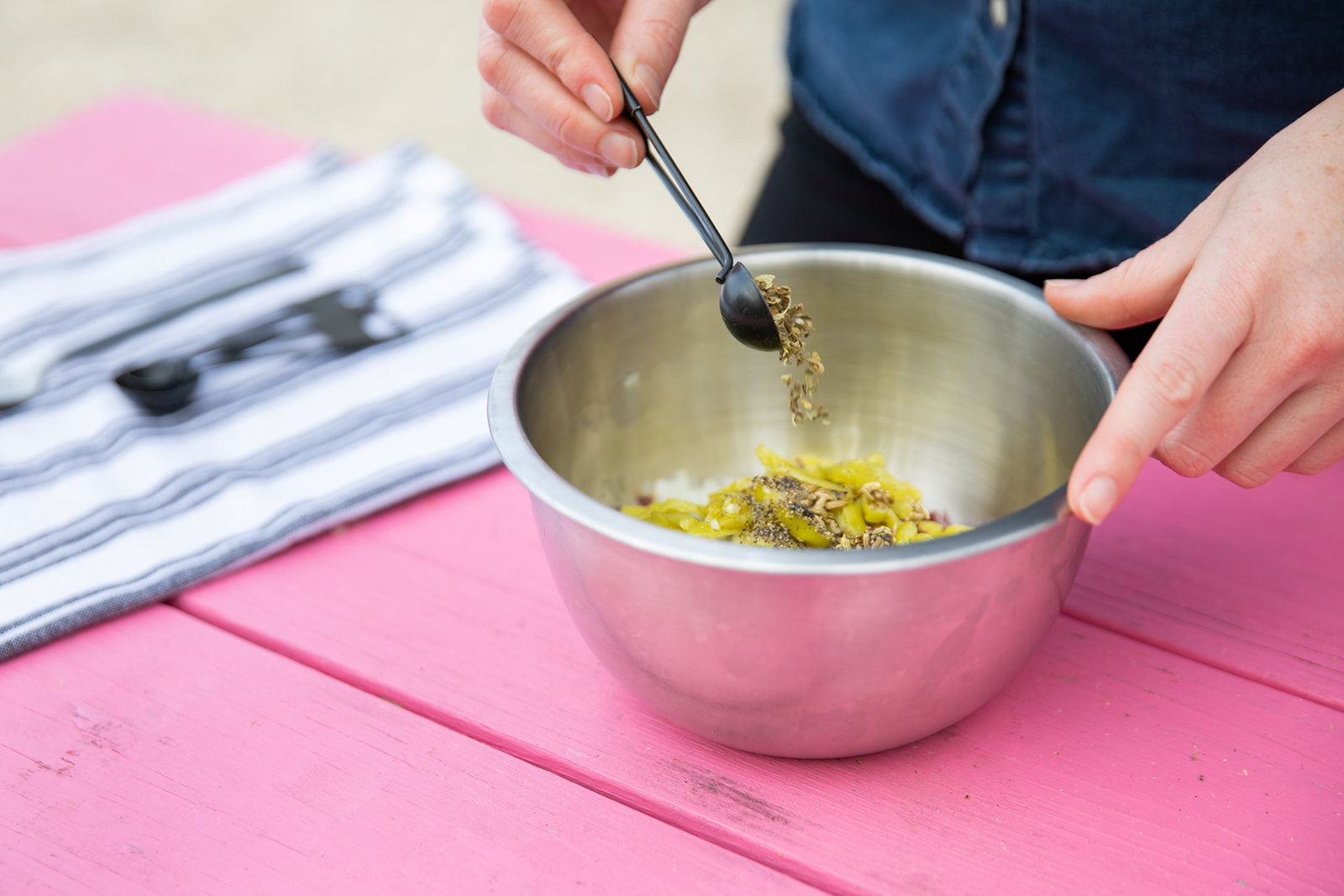 Mixing peppers, capers and olives together in a metal bowl. 