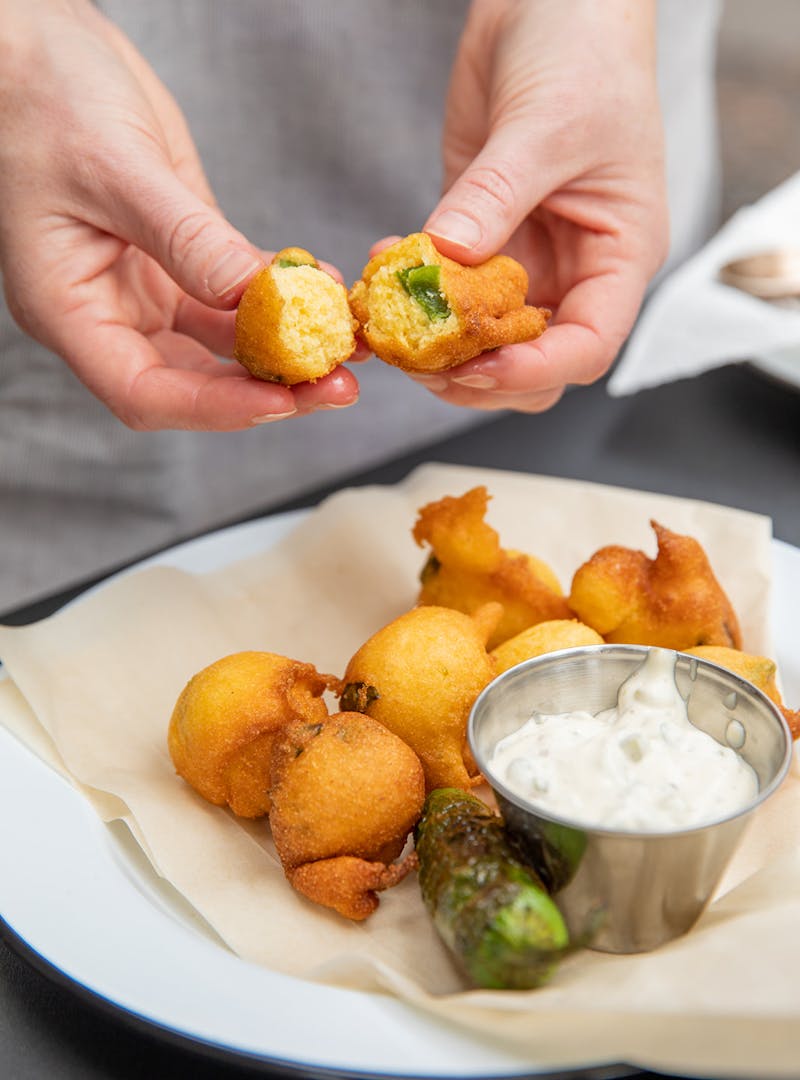 Cracking open a cooked hush puppy to reveal the jalapeño inside.