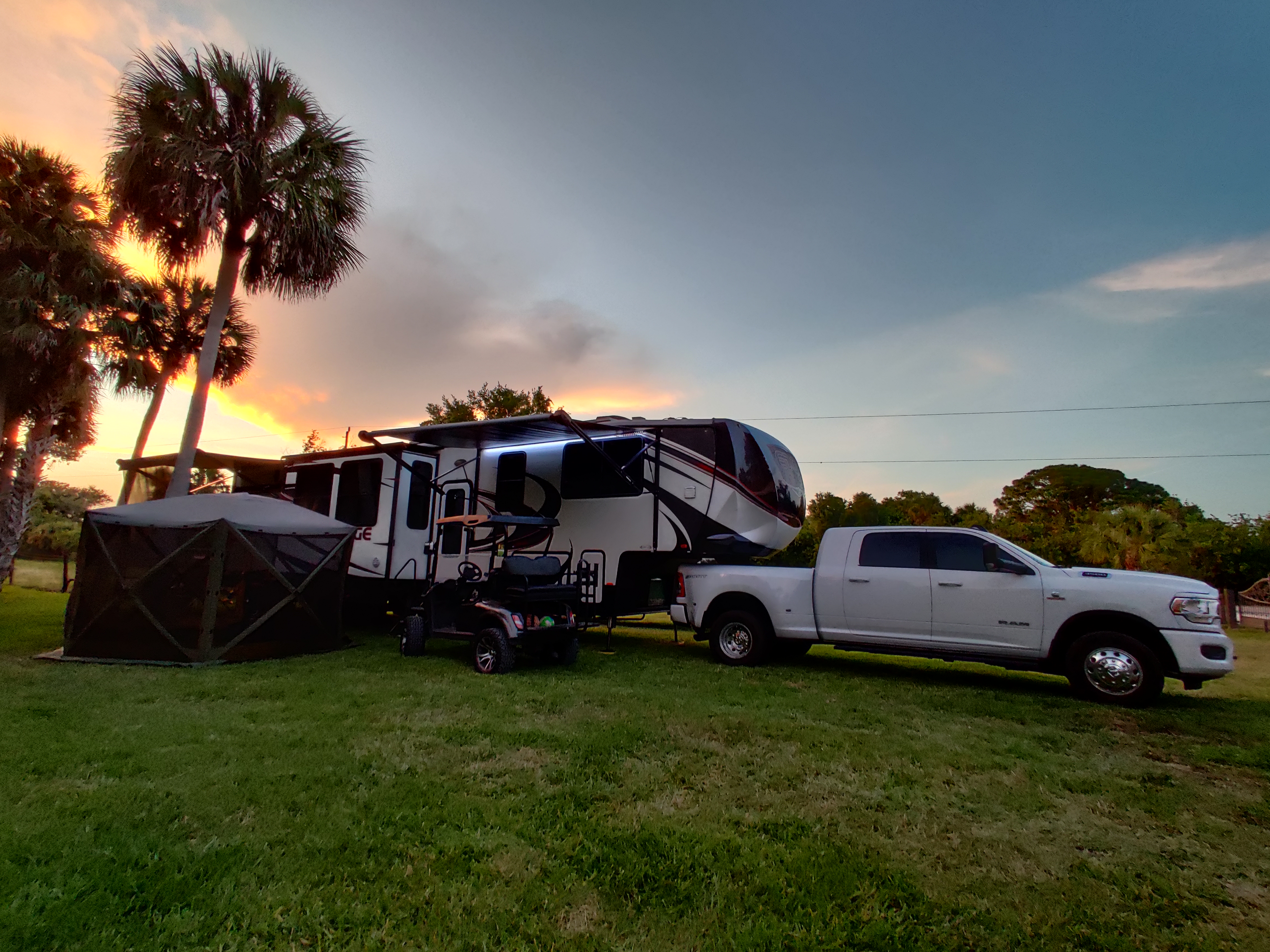 Sandra Crespo's RV parked on grass near palm trees at sunset