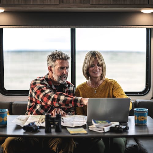 A couple pointing and looking at things on a computer