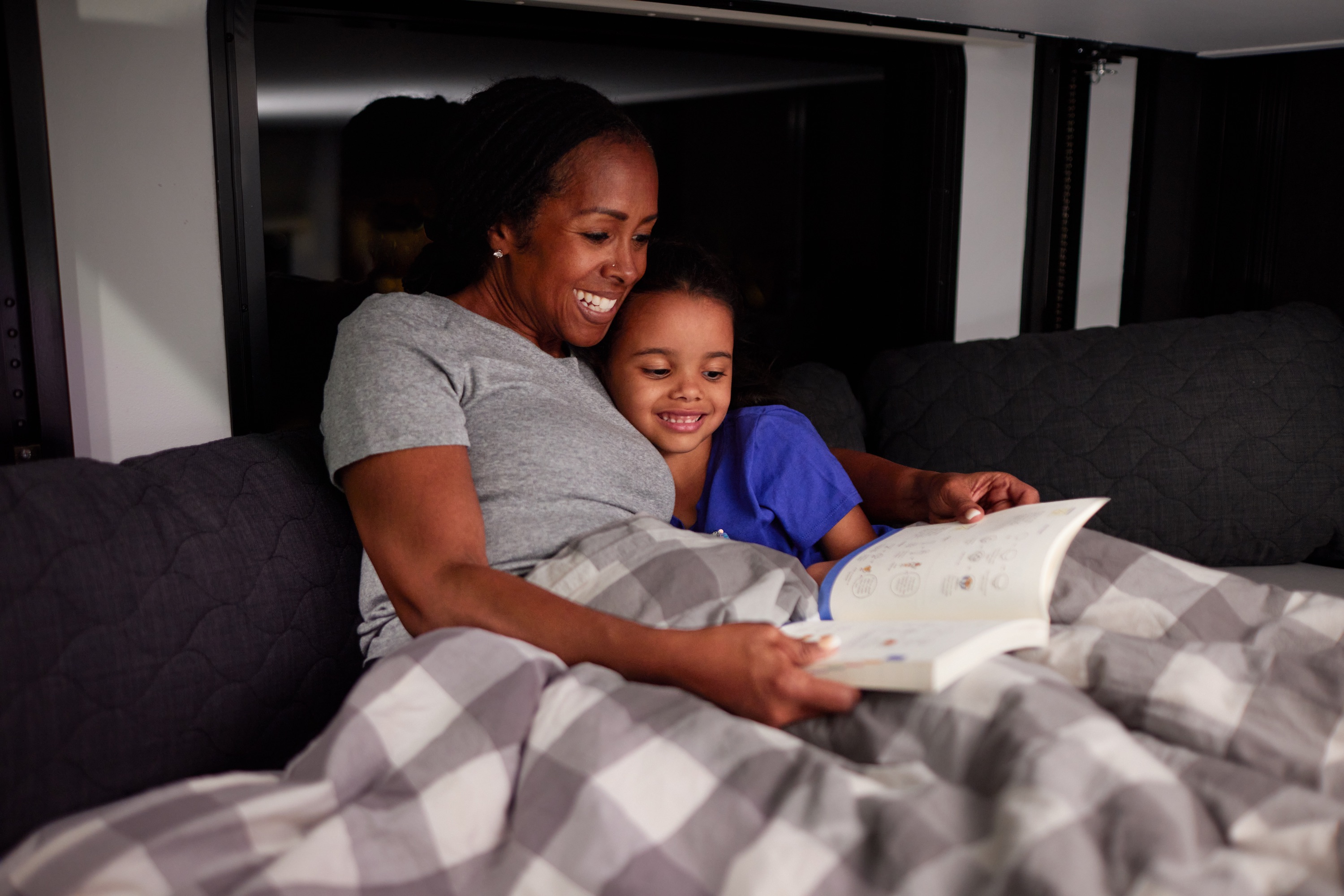 Robin reads a book to her granddaughter in one of the bunkbeds in their Keystone Fuzion toy hauler. 