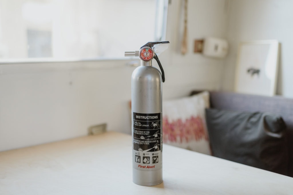 Silver fire extinguisher sitting on white table 