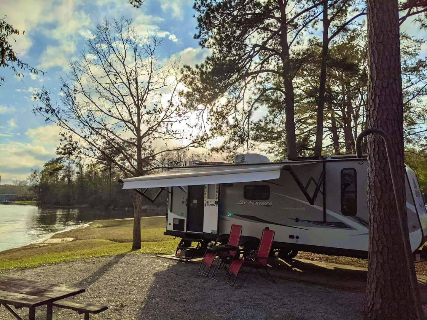 CHRISTINA AND BEN MCMILLAN's Jayco Jay Feather parked at a traditional campground next to a lake 