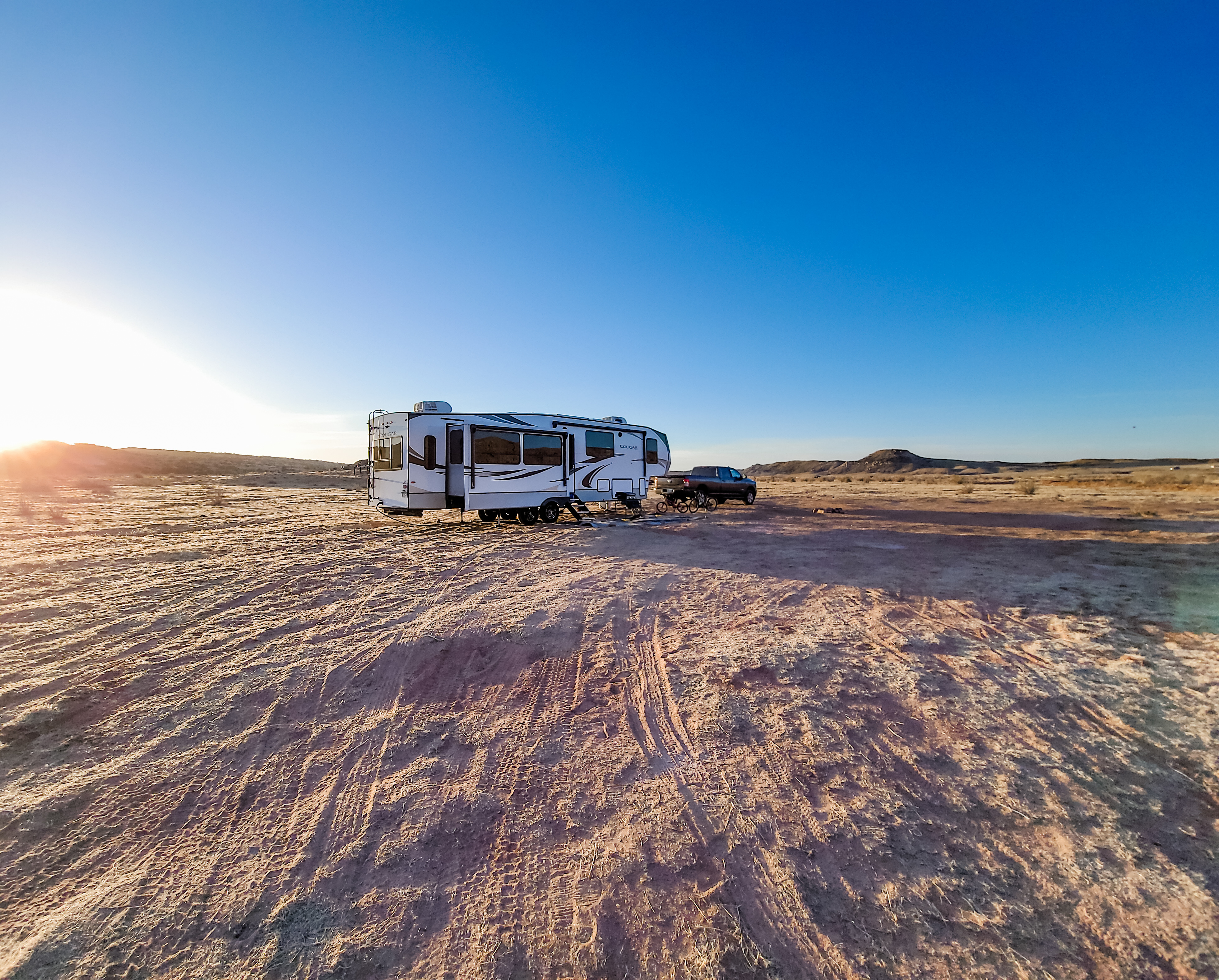 STEVE & KAYLEE TECHAU boondocking in their fifth wheel rv in a sandy landscape
