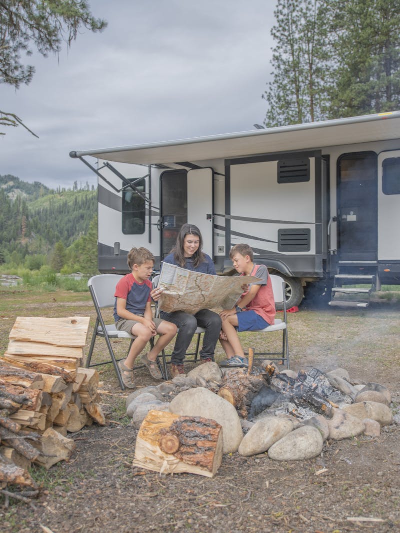 Chelsea Day looking at a map with her children in front of her Highland Ridge RV