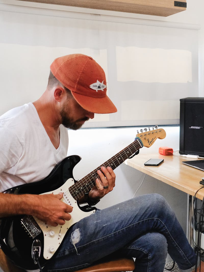 Amick Cutler plays guitar by a desk in an RV.