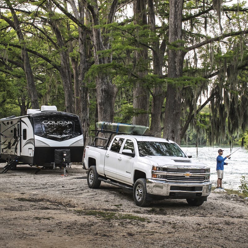 Robert Field fishes as the bank of a river next to his Cougar Travel Trailer and truck.