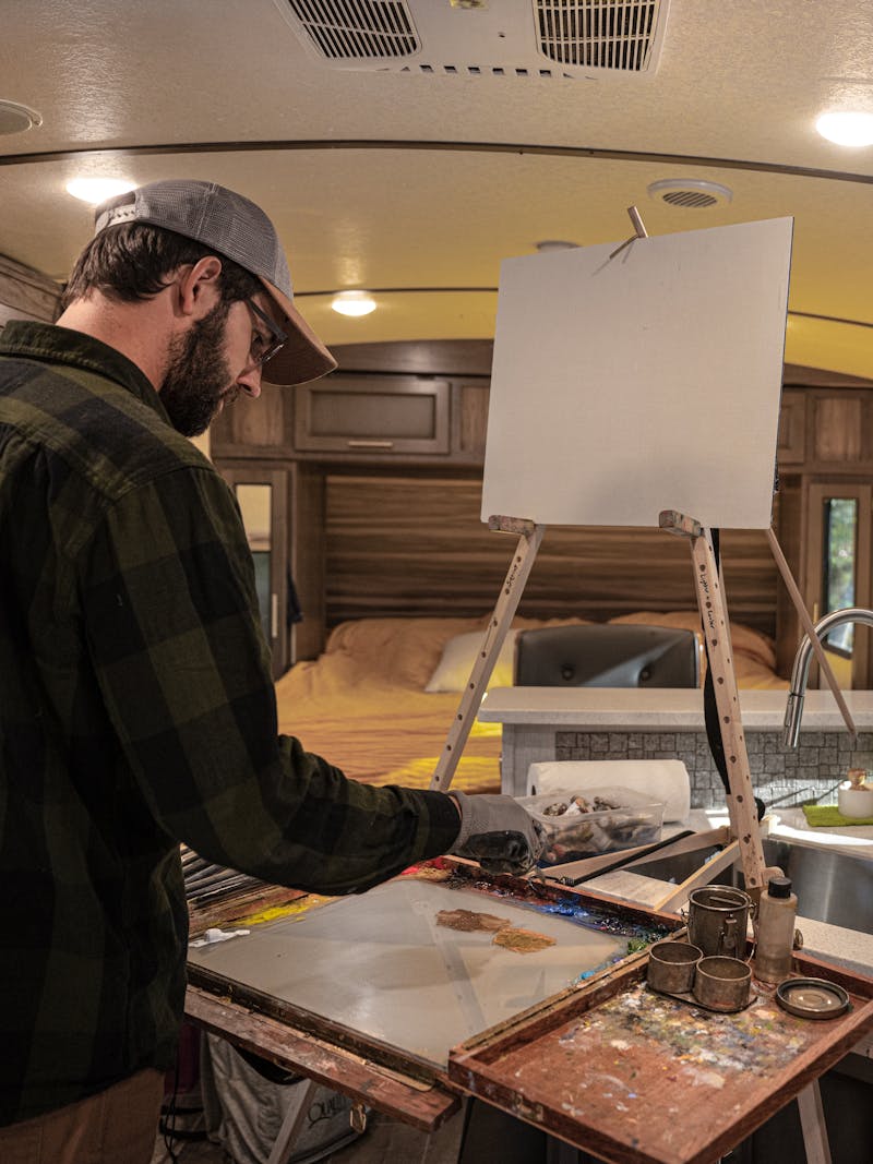 Todd Schabel painting a landscape inside his Crossroads Sunset Trail RV.