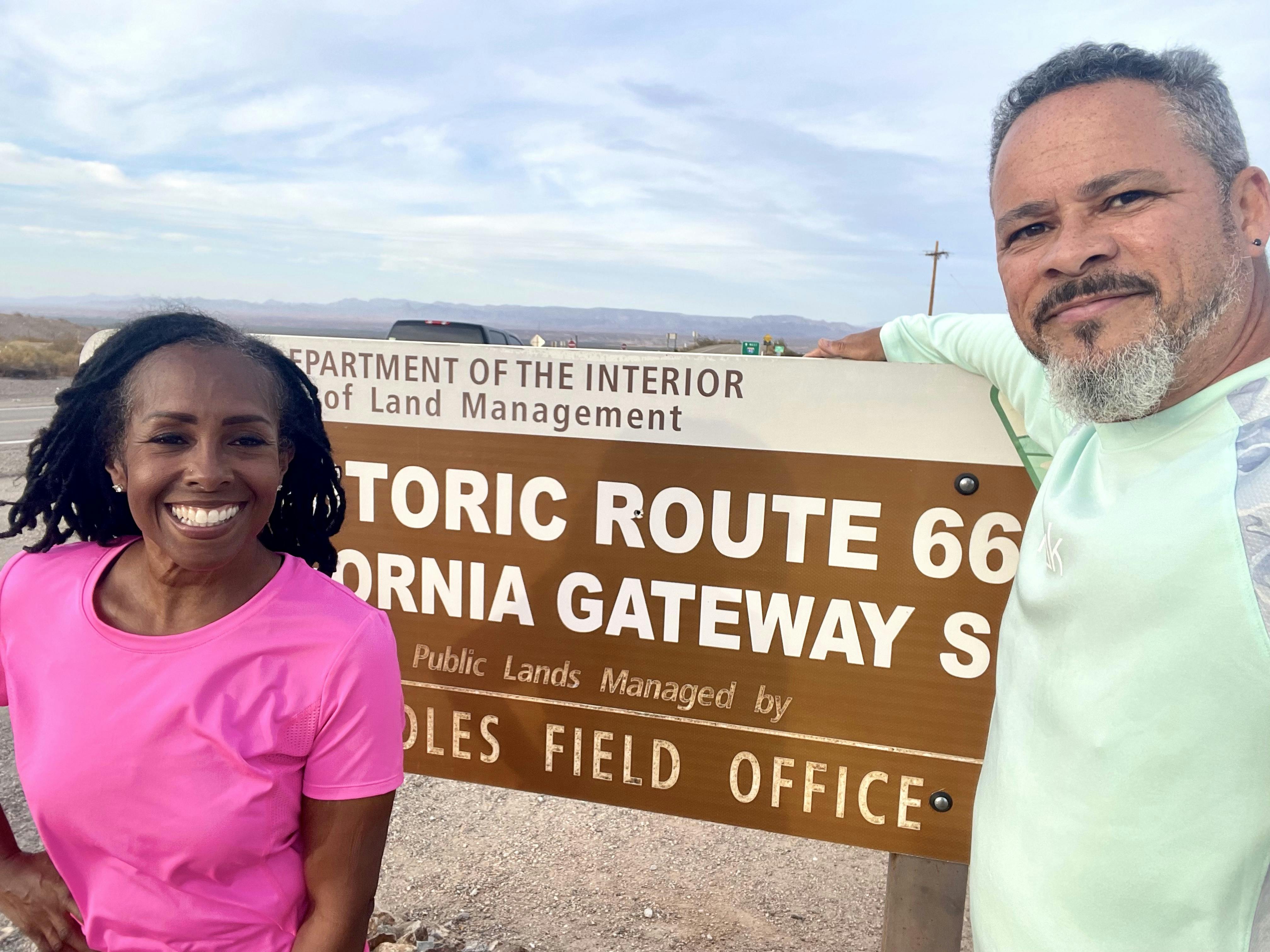 Robin and Warren Baxter smiling in front of the route 66 sign 