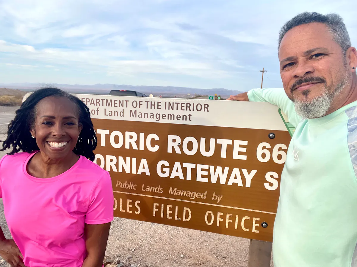 Robin and Warren Baxter smiling in front of the route 66 sign 
